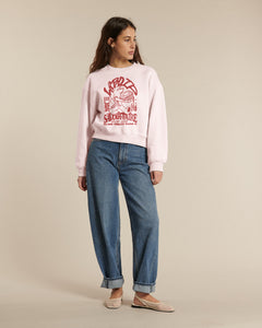 Femme portant un jean droit en denim bleu 100 % coton, associé à un sweat imprimé rose clair, look décontracté adapté à toutes les morphologies.