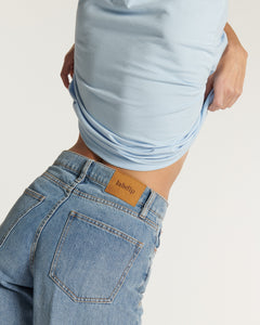 Jean en denim bleu clair 100 % coton avec coupe droite et taille haute, conçu pour s'adapter parfaitement à toutes les morphologies féminines.