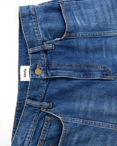 Jean en denim bleu mid-blue 100% coton avec coupe large, taille moyenne et détails couture apparents, conçu pour s’adapter à toutes les morphologies féminines.