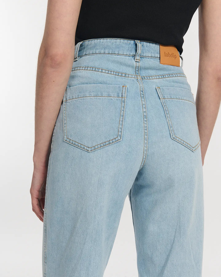 Jean droit en denim bleu clair 100 % coton avec taille haute et coupe large, s'adaptant parfaitement à toutes les morphologies féminines.