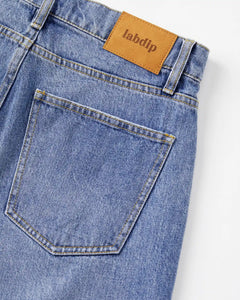 Jean en denim bleu clair 100% coton avec coupe droite, matière rigide et poche arrière classique, idéal pour femme et adapté à toutes les morphologies.
