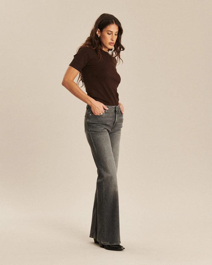 Jean en denim gris clair en coton, coupe bootcut ajustée à la taille et évasée aux chevilles, offrant un style féminin et confortable.