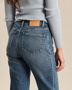 Jean en denim bleu moyen avec coupe bootcut ajustée, tissu en coton offrant confort et souplesse, conçu pour épouser toutes les morphologies féminines.