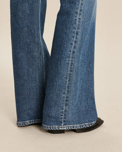 Jean femme en denim 100 % coton bleu moyen avec coupe bootcut évasée à partir du genou, offrant un tombé fluide et un ajustement confortable.