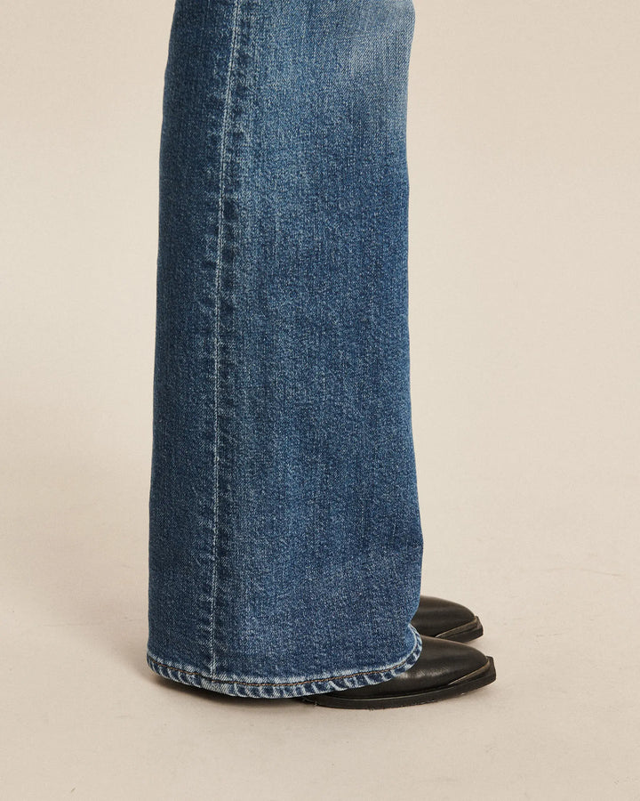 Jean en denim bleu moyen avec une coupe bootcut, matière en coton épaisse et finition nette, conçu pour épouser élégamment toutes les morphologies féminines.