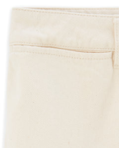 Détail de jean féminin en denim écru clair, matière 100% coton avec une coupe droite et un tissage visible pour un style estival naturel et élégant.