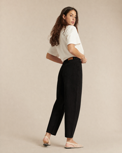 Jean femme en denim noir 100% coton avec coupe ballon et taille haute, offrant un confort léger et une silhouette décontractée adaptée à toutes les morphologies.
Porté par le mannequin de profil