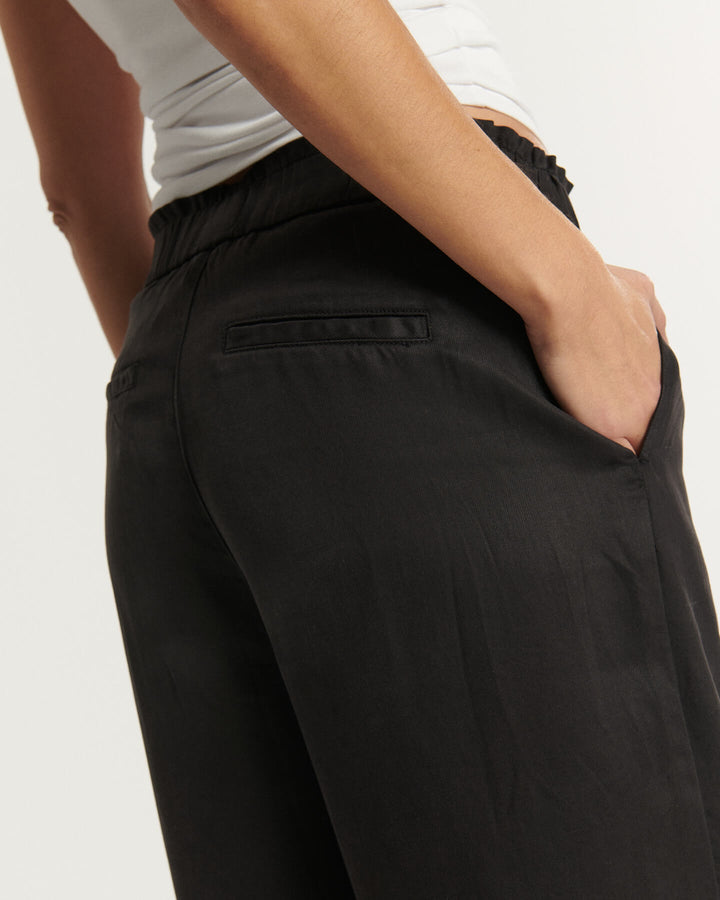 Jean noir en tissu fluide et léger, coupe droite avec taille élastiquée, offrant un ajustement confortable et adapté à toutes les morphologies féminines.