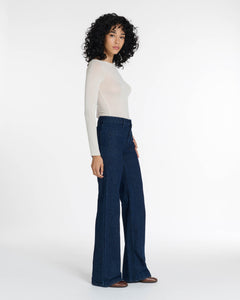 Jean femme en denim brut bleu foncé, coupe flare avec taille haute ajustée, matière 100 % coton offrant un tombé fluide et confortable adaptable à toutes les morphologies.
