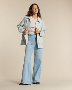 Jean en denim bleu clair avec une coupe flare, taille haute et ajustée aux hanches, idéal pour femme, offrant confort et style décontracté.