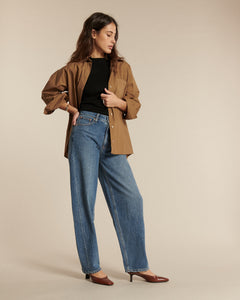 Jean femme en denim bleu clair avec coupe barrel, taille haute et tissu 100 % coton, offrant une silhouette confortable et élégante adaptée à toutes les morphologies.