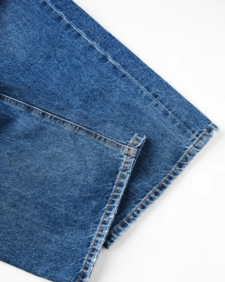 Jean en denim bleu moyen, coupe droite avec finitions soignées, tissu 100 % coton offrant confort et adaptabilité à toutes les morphologies féminines.