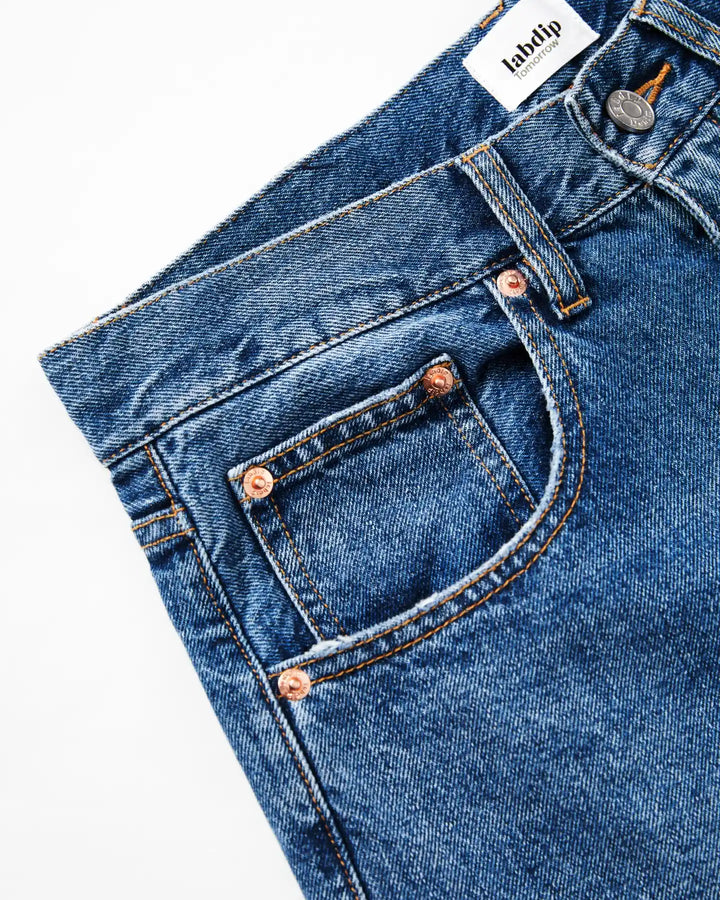 Jean en denim bleu mid avec une coupe droite classique, confectionné en coton épais et résistant, idéal pour un style féminin et confortable.