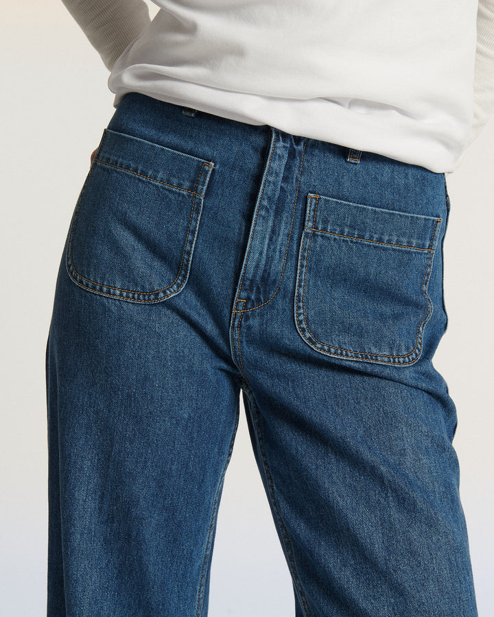 Jean en denim bleu moyen avec coupe droite et poches avant plaquées, conçu pour épouser toutes les morphologies féminines avec confort et élégance.