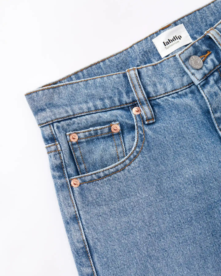 Jean en denim bleu clair 100 % coton avec coupe droite adaptée à toutes les morphologies féminines, finition soignée avec rivets cuivrés.