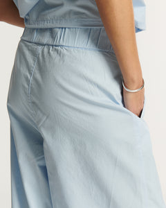 Pantalon en popeline légère bleu clair, coupe ample et fluide avec taille élastique pour un confort optimal, idéal pour un look estival féminin et décontracté.