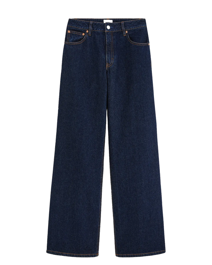 Jean femme en denim bleu foncé 100% coton avec coupe droite large, matière rigide et couture marron contrastante pour un style casual et adapté à toutes les morphologies.